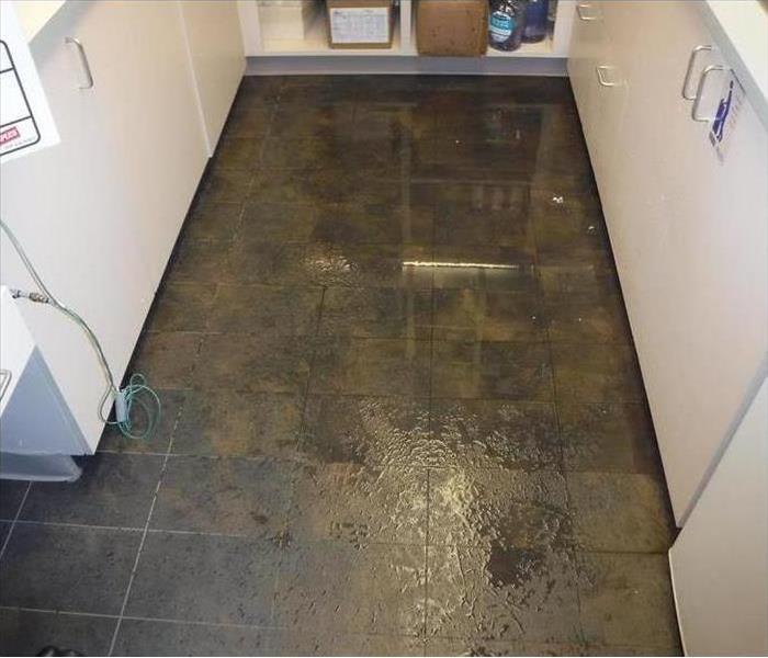 flooded brown floor with white cabinets on side 